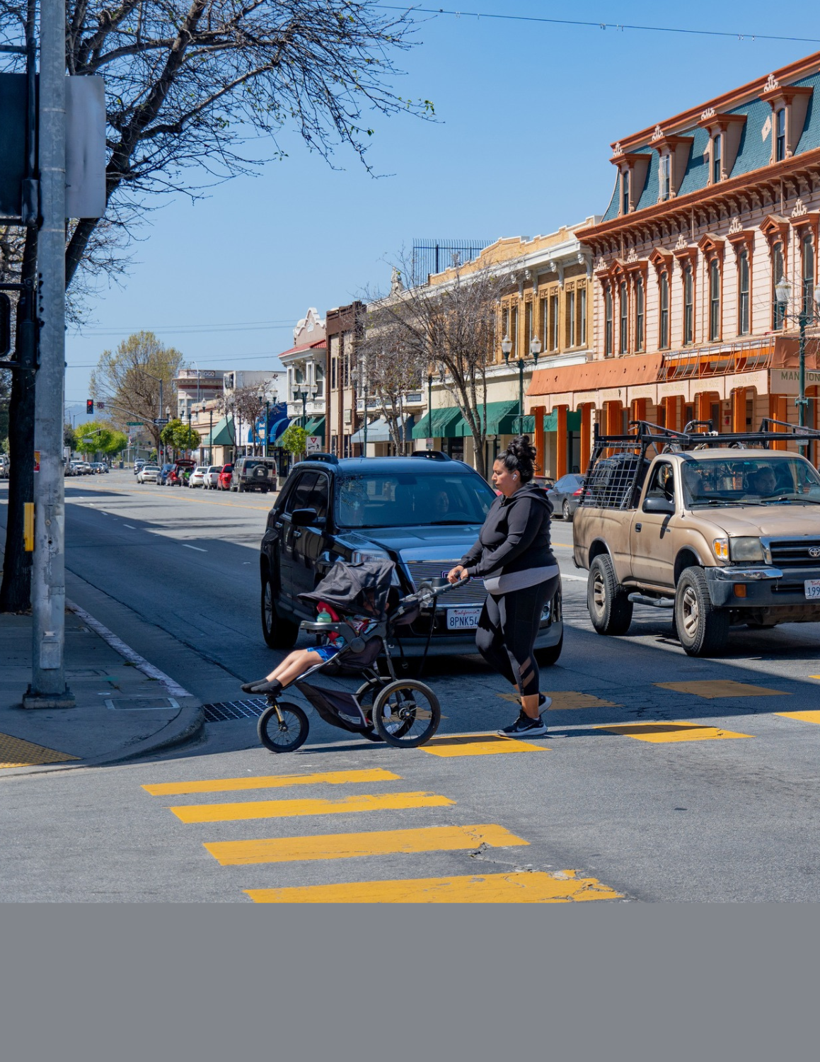 Woman pushing stroller crossing the street at an intersection