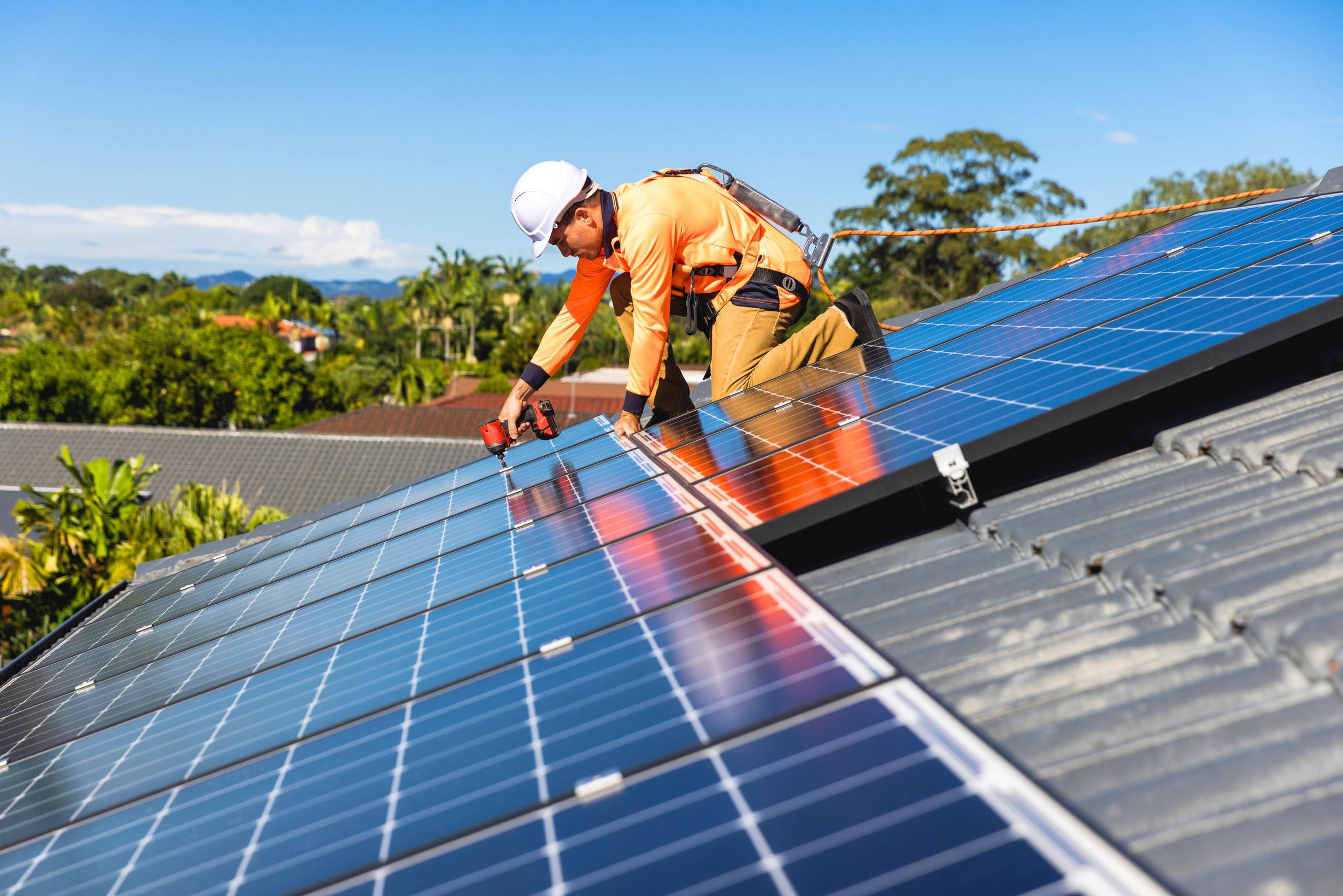 Image of a tradesman installing solar panels on a roof