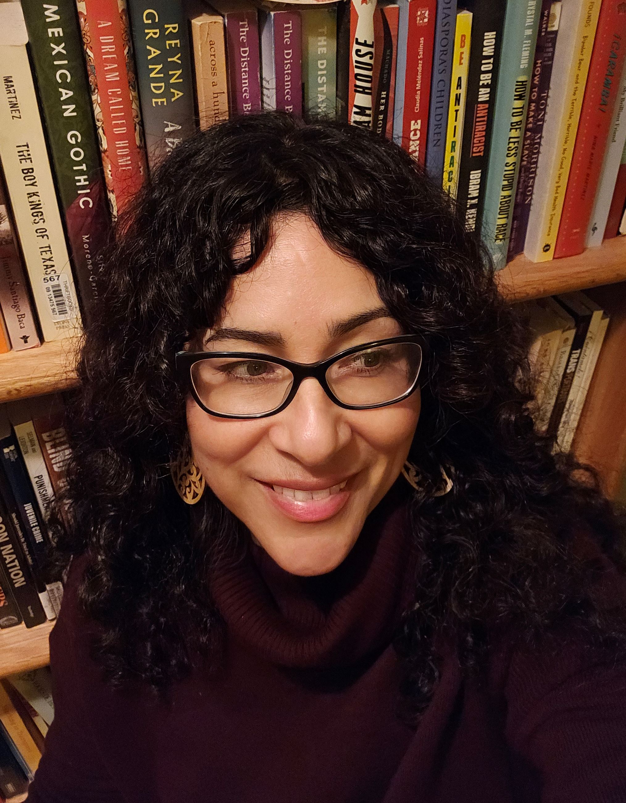Photo of Dr. Victoria Bañales with books in the background