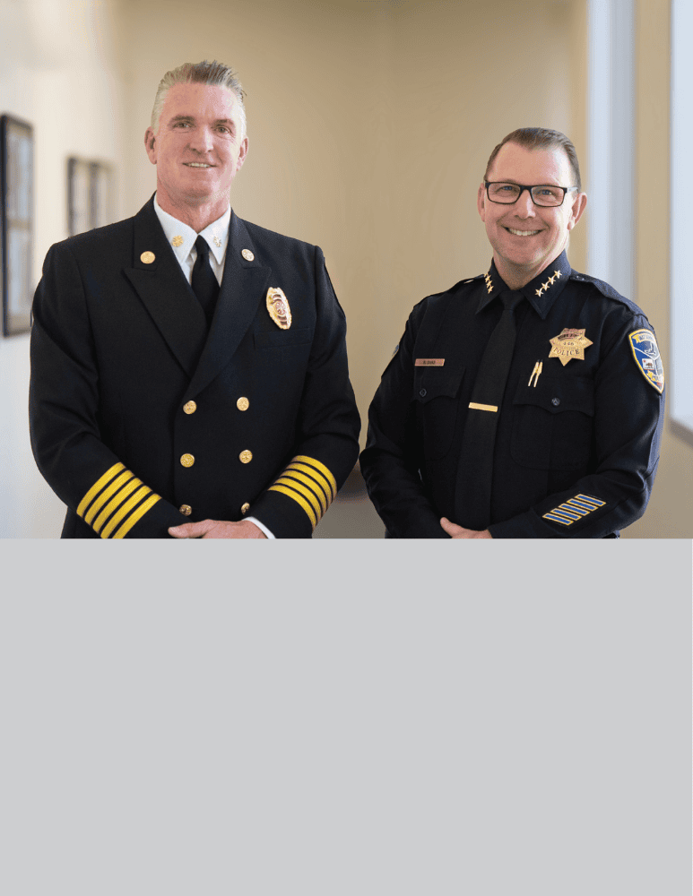 Fire Chief Corey Schaefer and Police Chief Brian Shab stand side by side indoors.